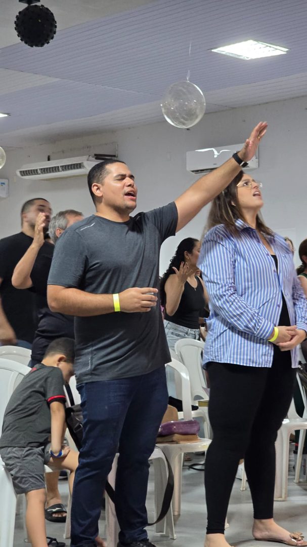 Membros da igreja louvando com as mãos levantadas